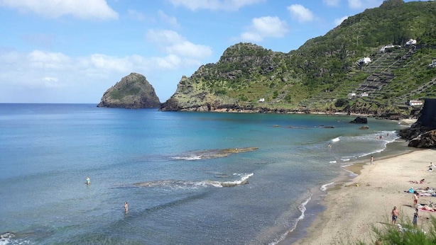 A coastal beach with clear waters, rocky outcrops, and a hillside with buildings. - Casa dos Magalhães (Vila do Porto)