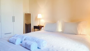 A neatly made bed with rolled towels, a bedside lamp, and a wardrobe. - Casa dos Magalhães (Vila do Porto)