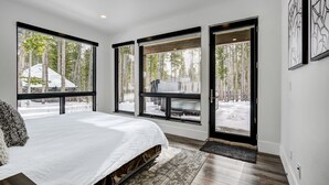 A bedroom with a large bed, a view of a snowy landscape, and a sliding glass door leading outside.