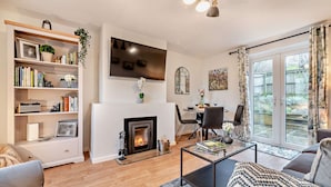 A modern living room with a fireplace, a dining area, and a large window with curtains.