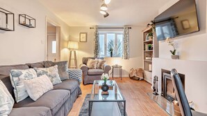A living room with a sofa, coffee table, fireplace, TV, and a bookshelf.
