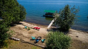 A lakeside cabin with a dock extending into the water, surrounded by trees and a clear view of the lake. - Lake Front New Remodel w/ Hot Tub- Coeur d'Alene (Coeur d'Alene)