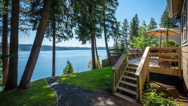 A deck with a wooden staircase leading to a house with a view of a lake and mountains. - Lake Front New Remodel w/ Hot Tub- Coeur d'Alene (Coeur d'Alene)