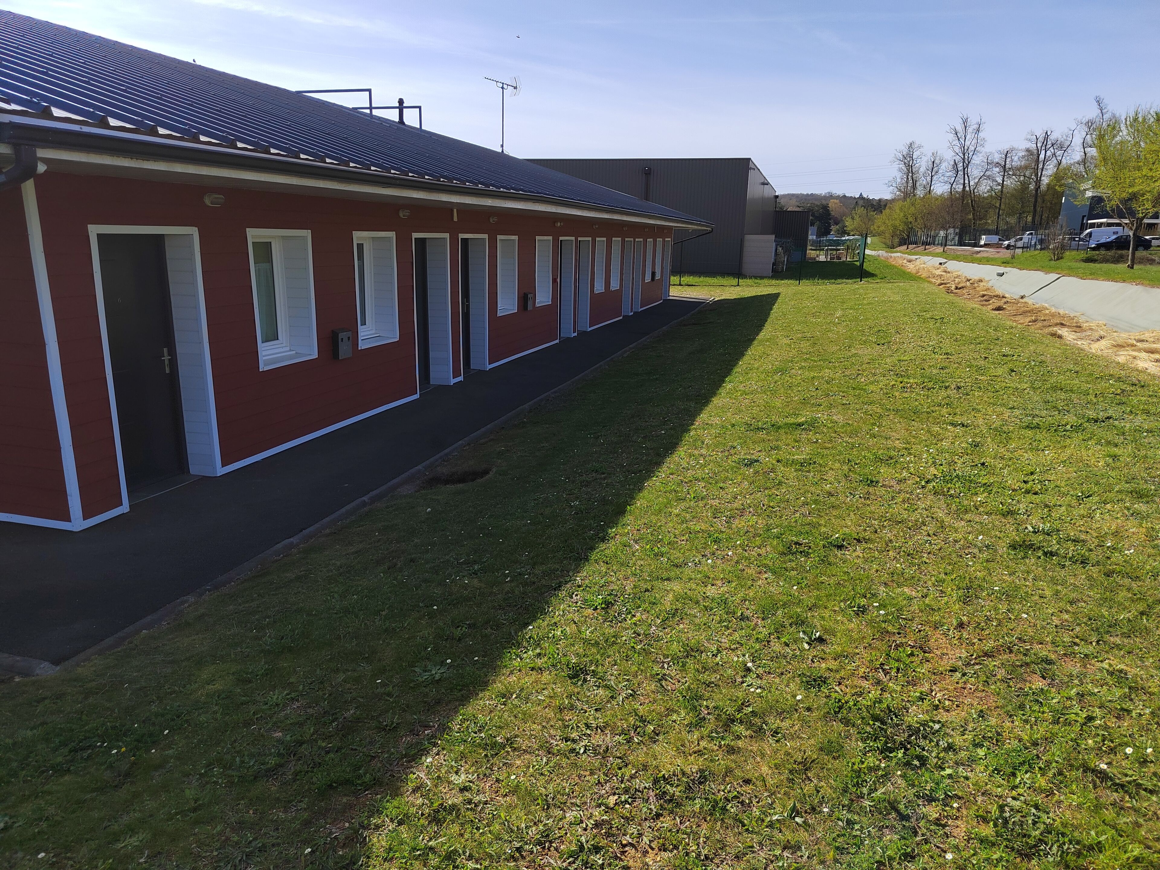 A row of red buildings with white trim, a grassy area, and a clear sky.