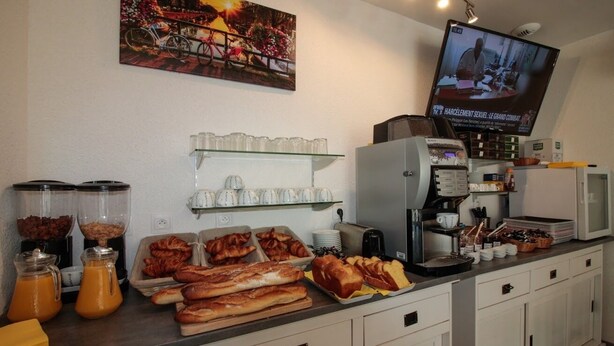 A breakfast buffet with various food items and a television displaying a news program. - Hôtel le 15 (Coulounieix-Chamiers)