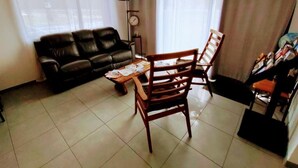 A living room with a sofa, wooden chair, and a coffee table. - Hôtel le 15 (Coulounieix-Chamiers)