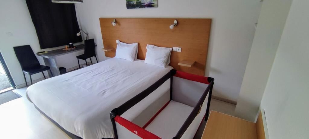 A hotel room with a bed, a desk, two chairs, and a wooden headboard.