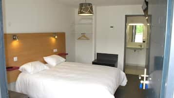 Habitación de hotel con cama, mesitas de noche, lámpara colgante, un banco, un espejo y una puerta que da al baño.