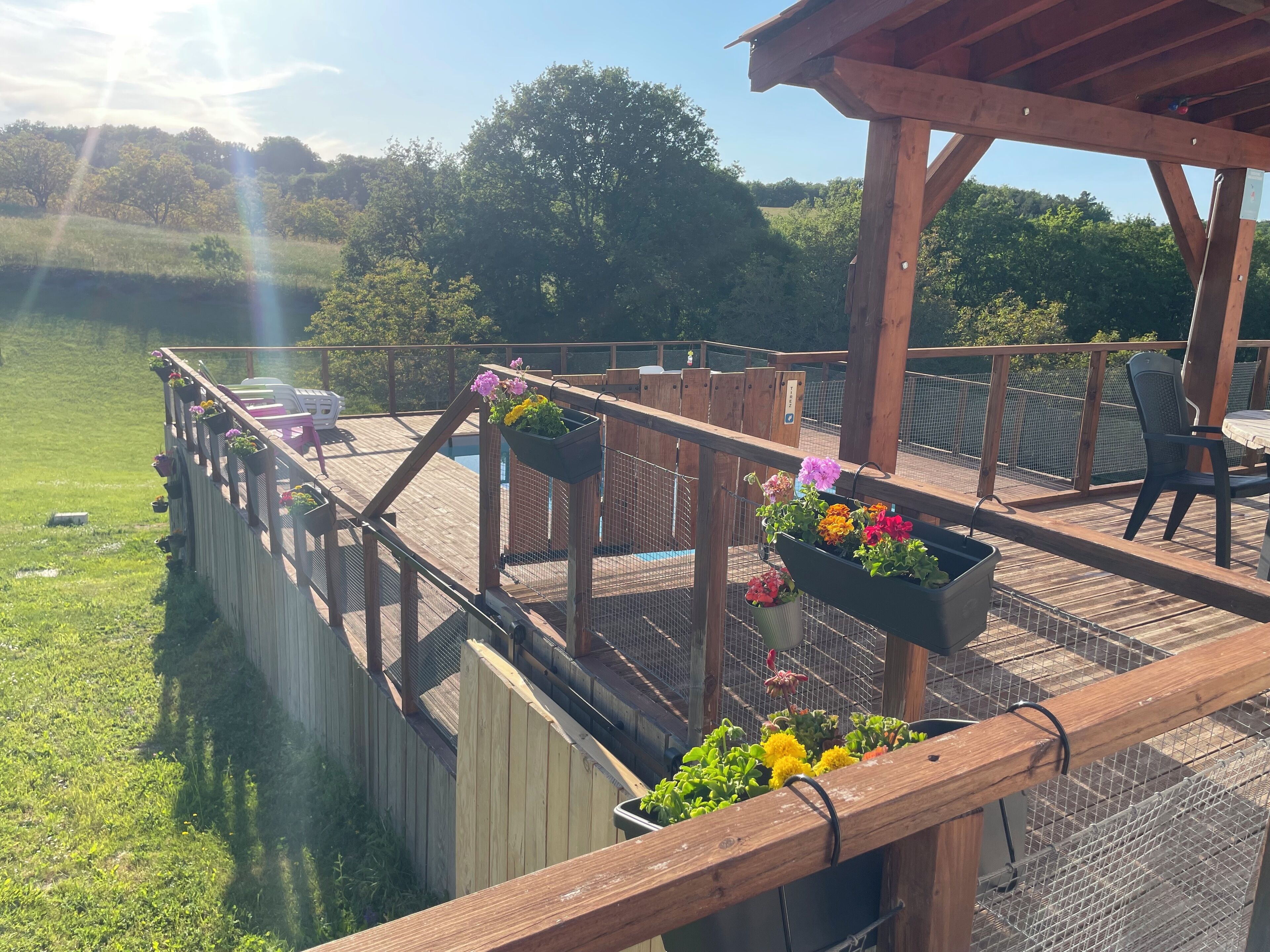 En træterrasse med udsigt over en sø, omgivet af et træhegn.
