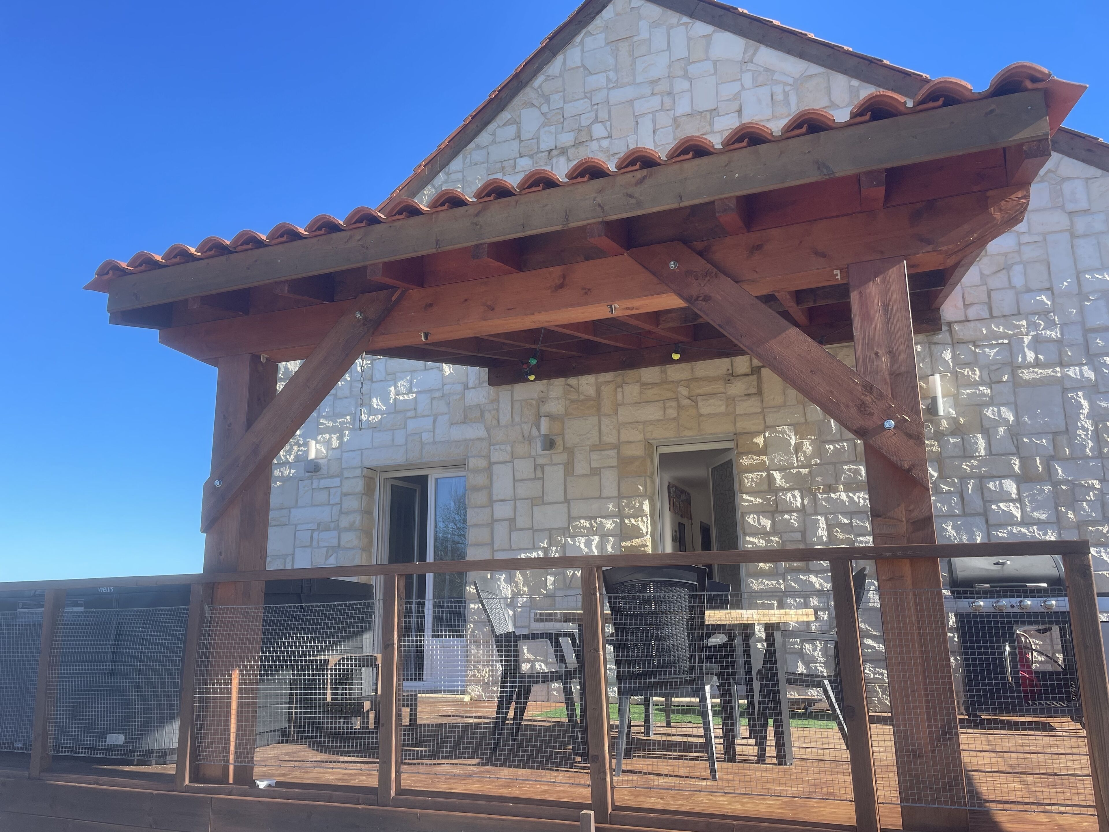 A stone building with a wooden pergola entrance.