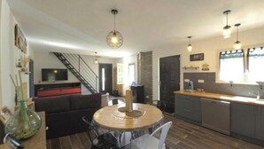 Une cuisine moderne avec un coin repas, comprenant une table ronde, des chaises et un escalier menant à un autre niveau.