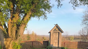 A rustic outdoor setting with a wooden fire pit, picnic tables, and a small wooden structure. - Inn the Barn (Conestoga)