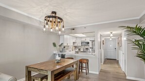 Una cocina moderna con armarios blancos, una mesa de comedor de madera y una araña.