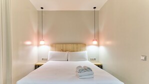 Habitación de hotel con una cama grande, dos mesitas de noche y dos lámparas colgantes.