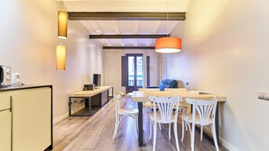 Una cocina moderna con comedor, suelo de madera e iluminación colgante.