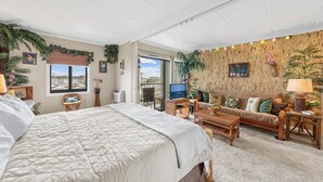 A spacious room with a large bed, a sofa, a TV, and a balcony with a view. - Westward Ho 410 by Seaside Vacations & Sales (Ocean City)