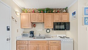 A kitchen with wooden cabinets, a microwave, a stove, and a sink. - Westward Ho 410 by Seaside Vacations & Sales (Ocean City)