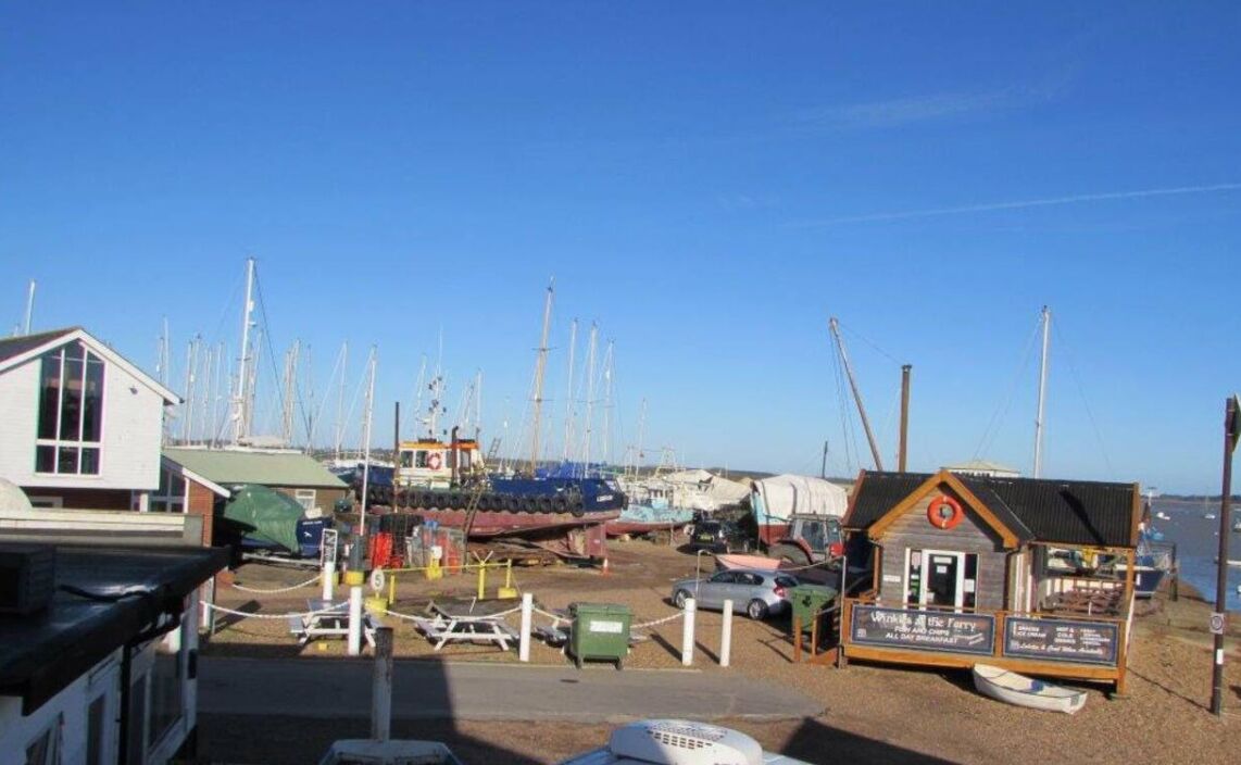 A marina with boats docked, a small building with a sign, and a clear blue sky.