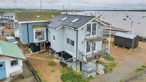 A coastal house with a balcony, a small deck, and a view of the sea. - The Old Pilot Hut, Felixstowe Ferry, Amazing Views (Felixstowe Ferry)
