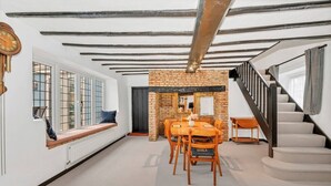 A dining area with a brick wall, wooden table, and chairs. - Charming Cottage in Barton Mills (Barton Mills)