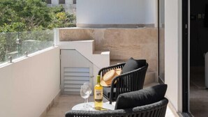 A balcony with two black chairs, a table, a bottle of alcohol, and a glass. - 2 BD w/ Private Plunge Pool + Terrace (Tulum)