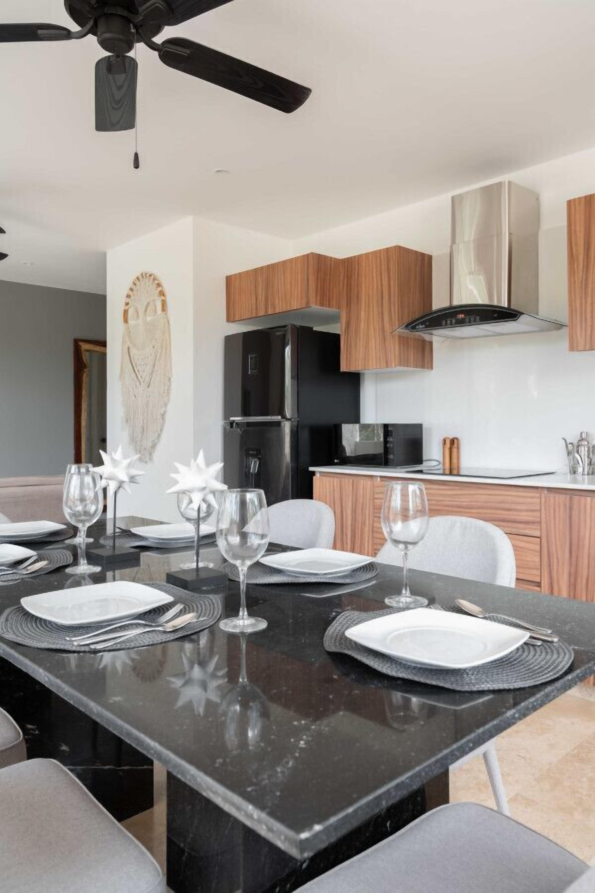 A modern kitchen with wooden cabinets, a black refrigerator, and a microwave.