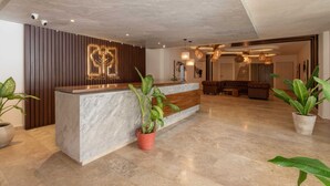 A reception area with a wooden panel wall, a marble counter, and potted plants. - 2 BD w/ Balcony and Rooftop Pool (Tulum)