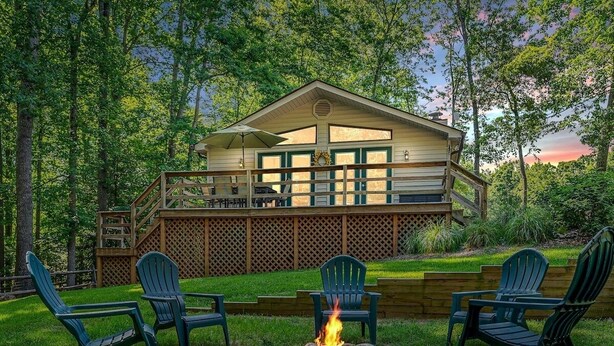 A cabin with a deck, outdoor seating, and a fire pit.