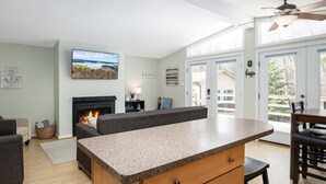 A modern living room with a fireplace, a large TV, and a dining area with a table and chairs.