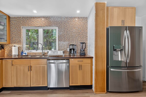 A modern kitchen with wooden cabinets, a stainless steel dishwasher, and a large refrigerator.