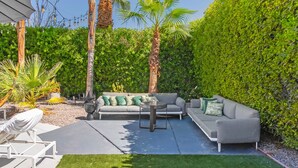 A patio area with a grey sofa set, a coffee table, and a white chair. - Casa Del Sol, a private Palm Springs Oasis (Palm Springs)