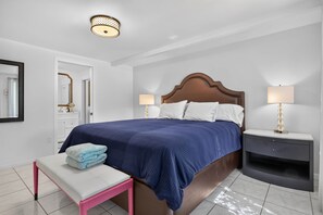 Une chambre d’hôtel avec un grand lit, des lampes de chevet, une table de chevet, un banc et un miroir.