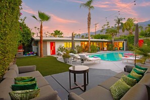 A modern outdoor pool area with lounge chairs, a small table, and a red door.