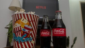 A popcorn container, two Coca-Cola bottles, and a Netflix logo on a wall. - Apartamento aconchegante - Caraguatatuba (Caraguatatuba)