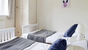 Un dormitorio con dos camas, un armario y obras de arte en la pared.