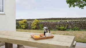 Una mesa de picnic de madera con una bandeja de comida y una cafetera.