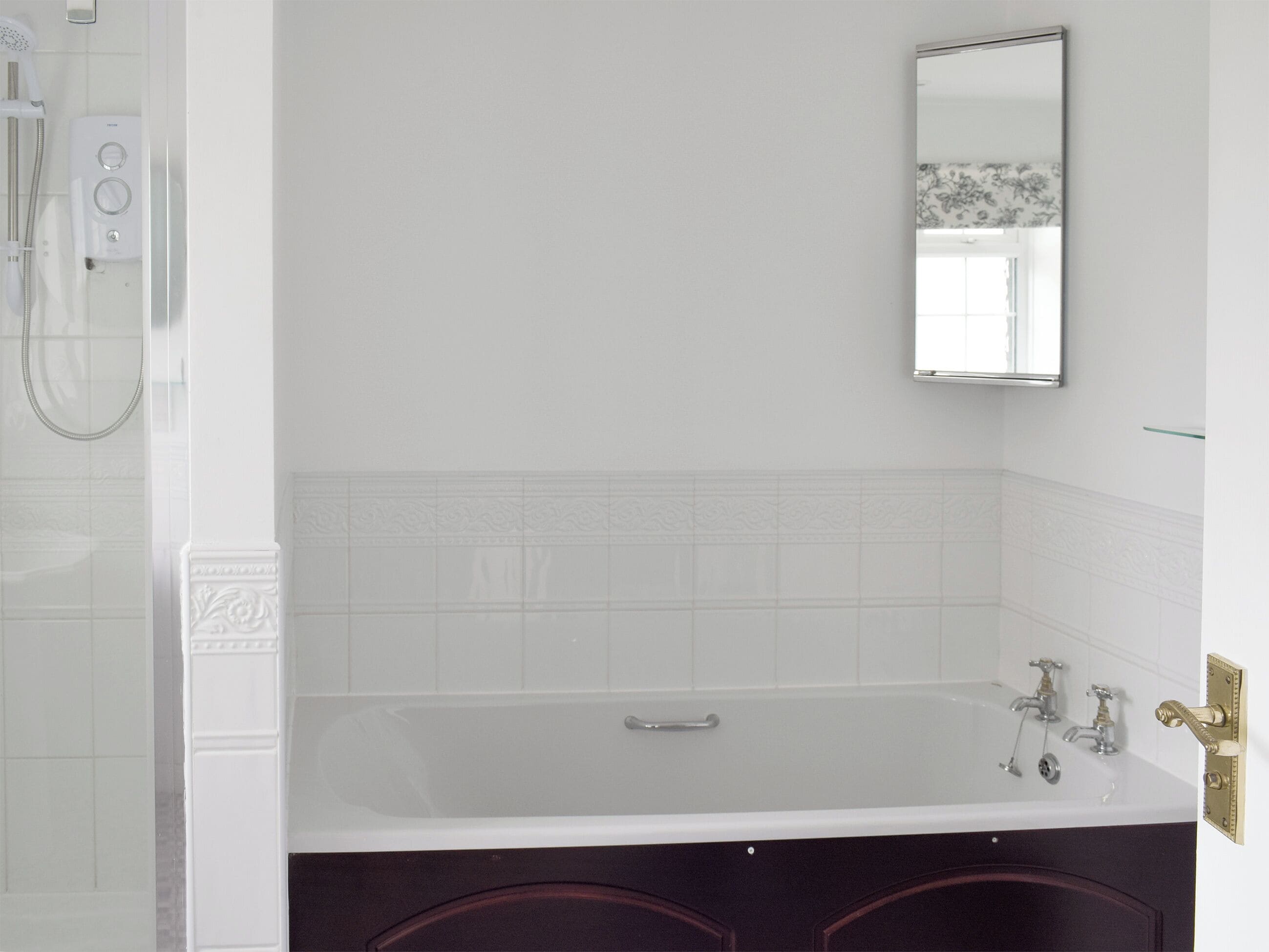 Een badkamer met een bad, een douche en een spiegel.