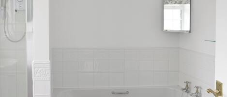 A bathroom with a bathtub, a shower, and a mirror.