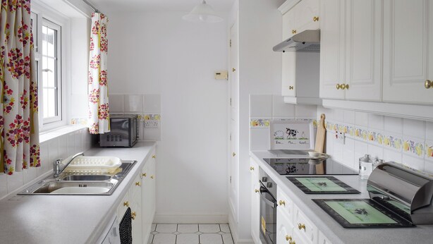 Cocina con gabinetes blancos, un lavamanos, un tostador y un microondas.