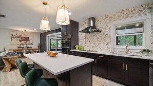 A modern kitchen with dark cabinetry, a large island, and pendant lighting.