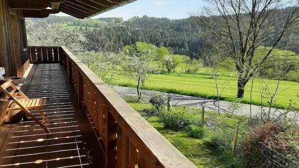 Eine Holzterrasse mit Blick auf eine grüne Landschaft und einen Fluss.