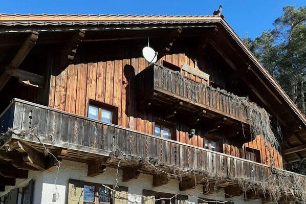 A wooden chalet with multiple balconies, a satellite dish, and a rustic appearance.