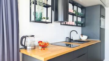 Cocina moderna con encimera de madera, un hervidor, un cuenco de fruta y una campana extractora negra.
