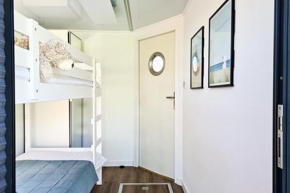 A bunk bed room with a door and two framed pictures on the wall.