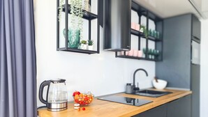 Une cuisine moderne avec un plan de travail en bois, une bouilloire, un saladier rempli de fruits et un évier.