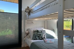 Un lit superposé avec une fenêtre, un ours en peluche et un magazine sur le lit.