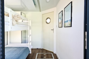 A room with bunk beds, a door with a round mirror, and framed pictures on the wall. - Houseboat in Łazy by Lake Jamno and Sea (Łazy)