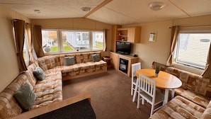 Een gezellig interieur van een camper met een modulaire bank, een eettafel en een televisieruimte.