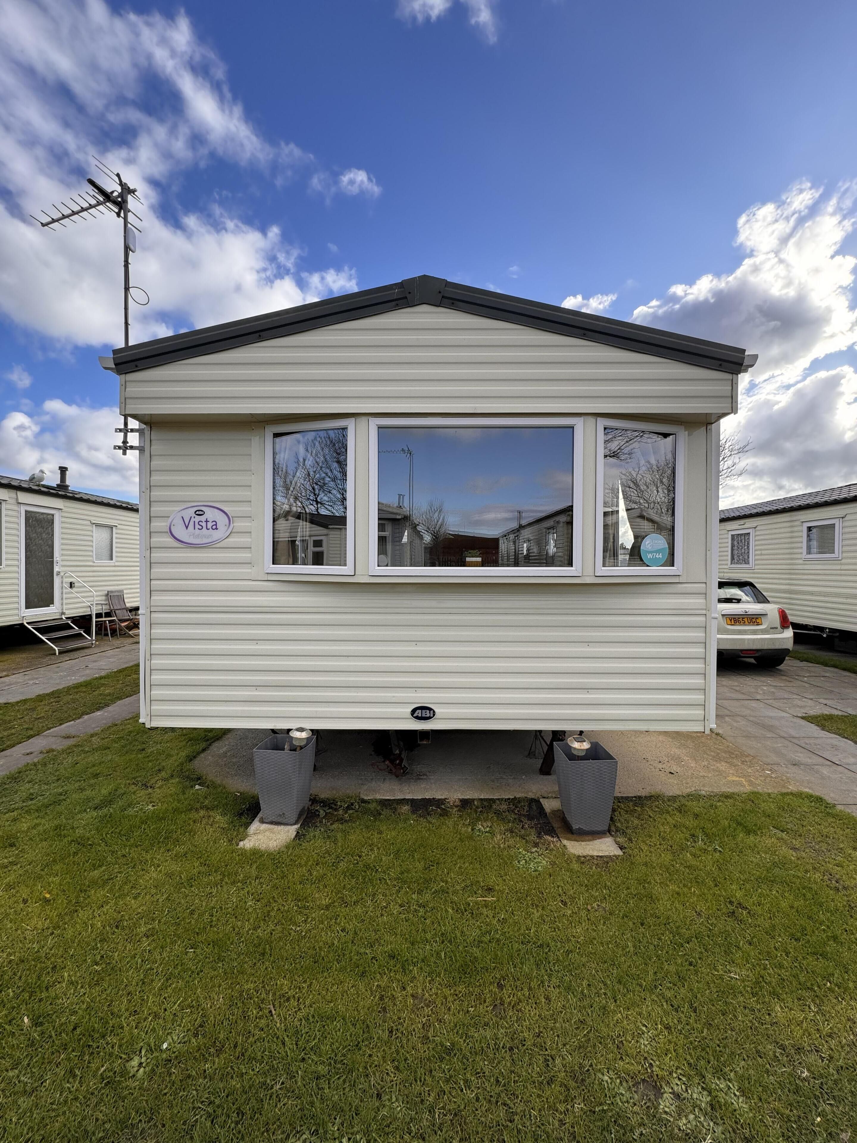 A mobile home with a small porch, a window with a view of the neighborhood, and a sign that reads "Vista."