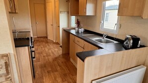 Een compacte keuken met houten kastjes, een spoelbak en een broodrooster.